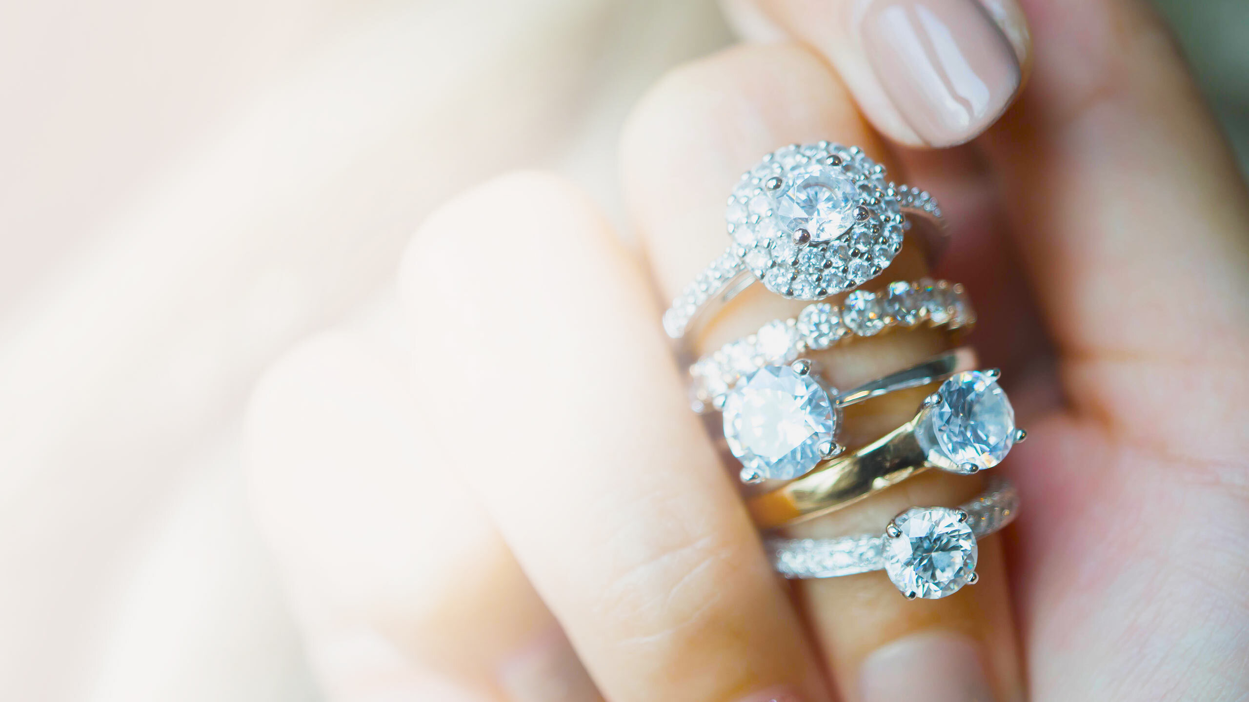 a stack of various style diamond rings displayed on a female hand